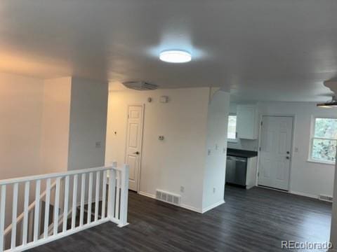 empty room featuring baseboards, visible vents, and dark wood-style floors