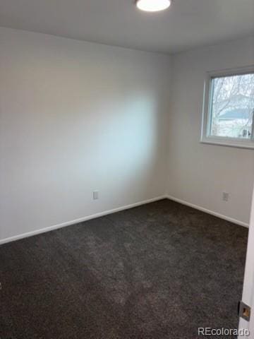 unfurnished room with dark colored carpet and baseboards