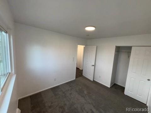 unfurnished bedroom featuring baseboards, a closet, and dark colored carpet