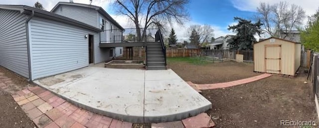 view of patio featuring an outdoor structure, fence, a deck, stairs, and a storage shed