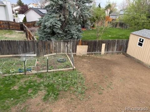 view of yard featuring a fenced backyard, an outbuilding, a vegetable garden, and a shed