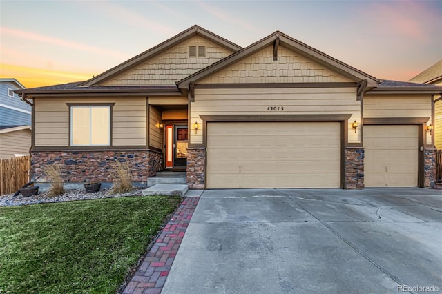 craftsman inspired home featuring a garage, concrete driveway, stone siding, fence, and a yard