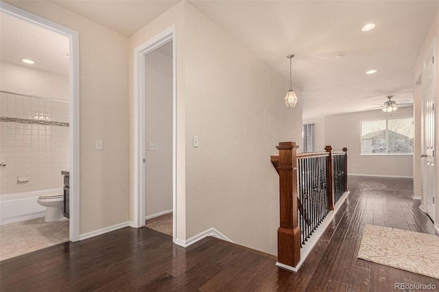 corridor with dark wood-style floors, recessed lighting, baseboards, and an upstairs landing