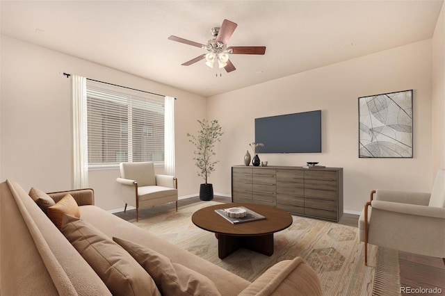 living area with ceiling fan and baseboards