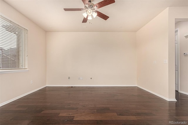 spare room with dark wood-type flooring, baseboards, and a ceiling fan