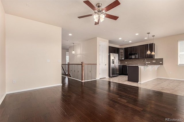 unfurnished living room with baseboards, recessed lighting, a sink, and light wood-style floors