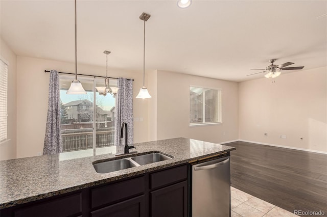 kitchen with pendant lighting, stainless steel dishwasher, stone countertops, open floor plan, and a sink