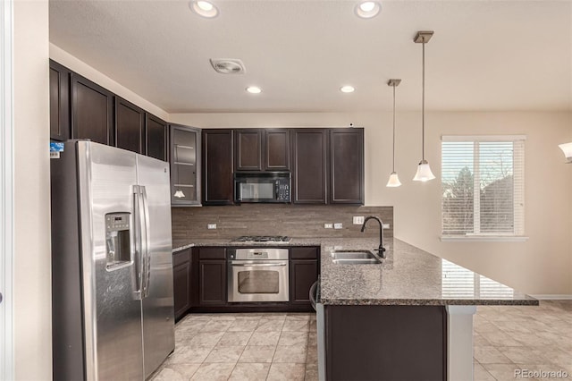 kitchen featuring dark brown cabinetry, a peninsula, a sink, visible vents, and appliances with stainless steel finishes