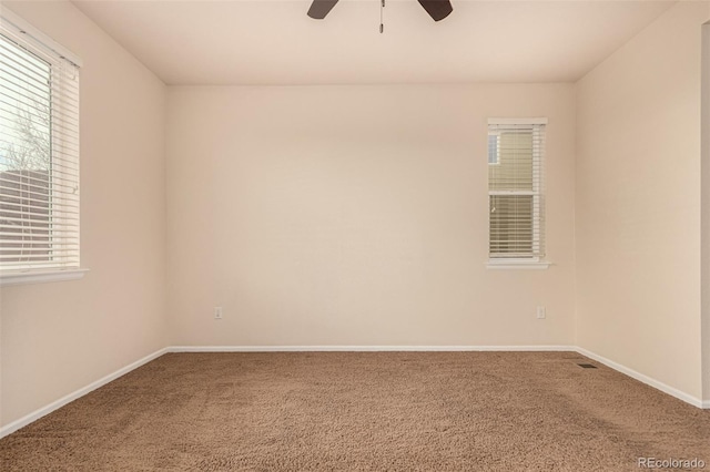 carpeted empty room with ceiling fan and baseboards