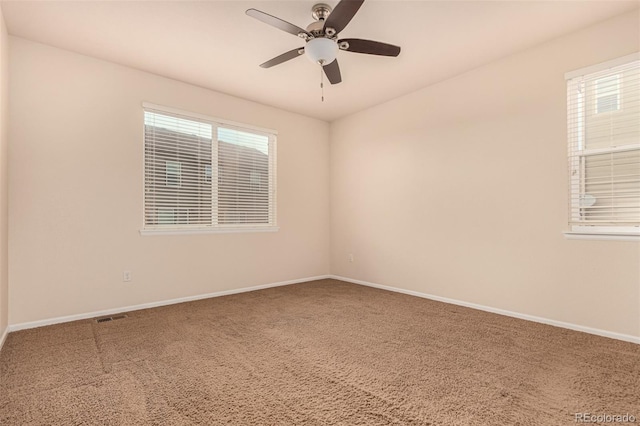 carpeted empty room featuring a ceiling fan, plenty of natural light, visible vents, and baseboards