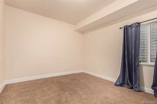 carpeted empty room featuring baseboards