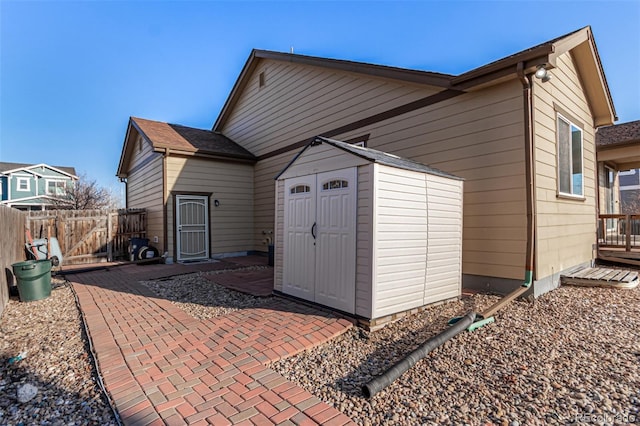 rear view of property with a storage shed, fence, a patio, and an outbuilding