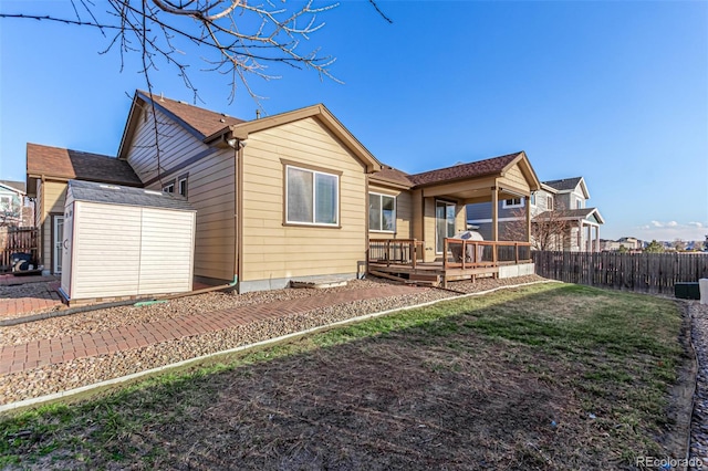 back of house with an outbuilding, fence, a lawn, a wooden deck, and a storage unit