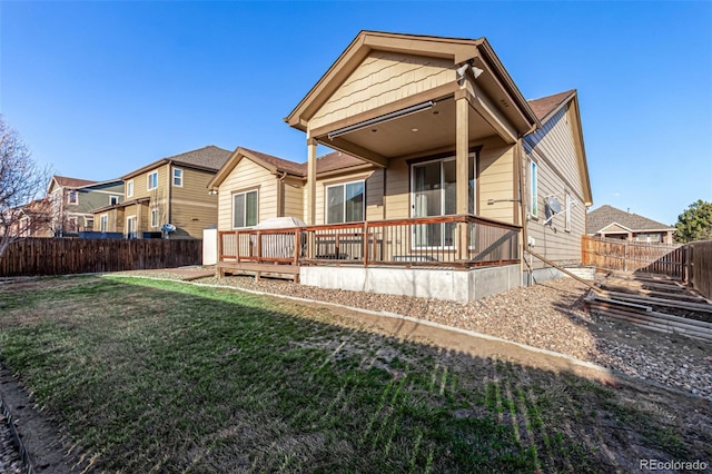 back of property with a fenced backyard, a wooden deck, and a yard