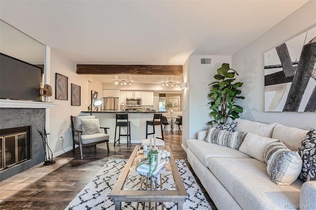 living room featuring beamed ceiling, wood-type flooring, and a tile fireplace