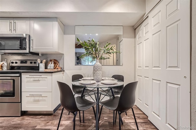 kitchen with appliances with stainless steel finishes, hardwood / wood-style flooring, and white cabinetry