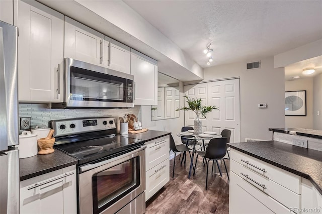 kitchen with white cabinetry, backsplash, appliances with stainless steel finishes, and dark hardwood / wood-style flooring