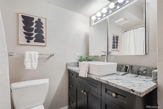 bathroom with vanity, a textured ceiling, and toilet