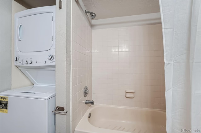 bathroom with shower / bath combo with shower curtain, a textured ceiling, and stacked washing maching and dryer