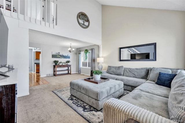 living area featuring visible vents, baseboards, carpet, a towering ceiling, and a notable chandelier