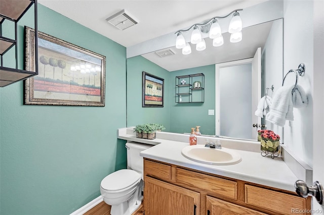 half bath featuring vanity, toilet, baseboards, and visible vents