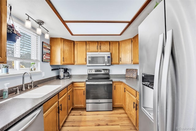 kitchen featuring a sink, stainless steel appliances, brown cabinets, and light wood-style flooring