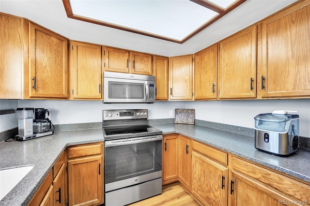 kitchen featuring a sink, stainless steel appliances, brown cabinetry, and light wood finished floors