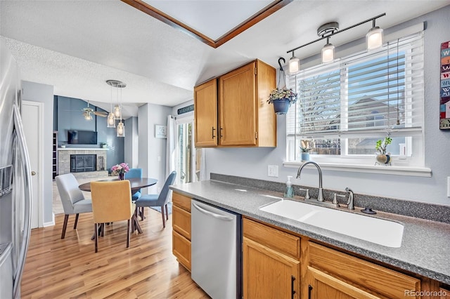 kitchen featuring a ceiling fan, light wood finished floors, a sink, stainless steel appliances, and a textured ceiling