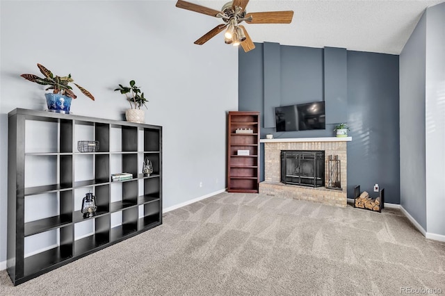 living room with a textured ceiling, carpet floors, a fireplace, baseboards, and ceiling fan