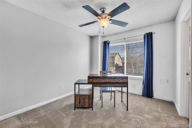 carpeted home office with a textured ceiling, baseboards, and ceiling fan