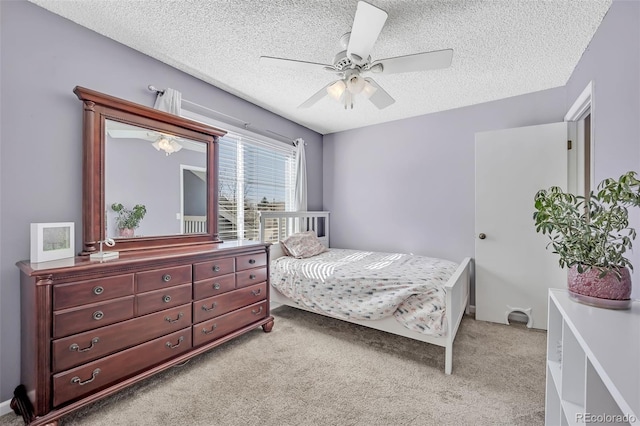 bedroom with a textured ceiling, ceiling fan, and light carpet