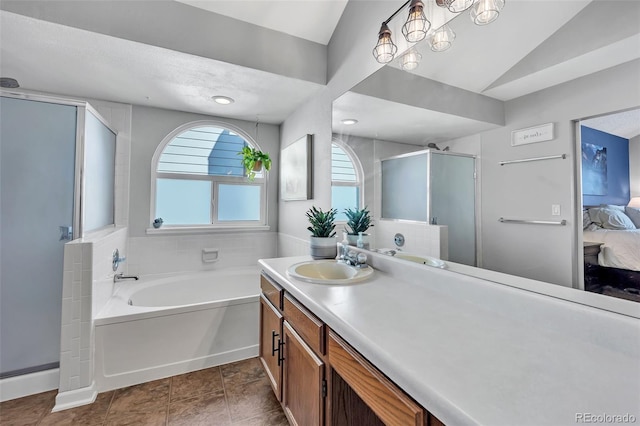 full bathroom with connected bathroom, a shower stall, a garden tub, vaulted ceiling, and vanity