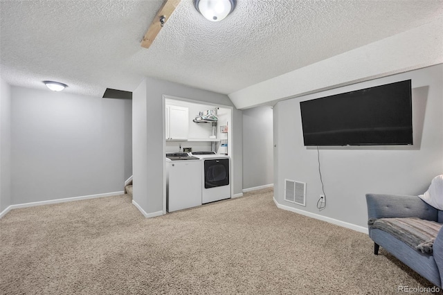 interior space featuring visible vents, a textured ceiling, baseboards, light colored carpet, and washing machine and clothes dryer