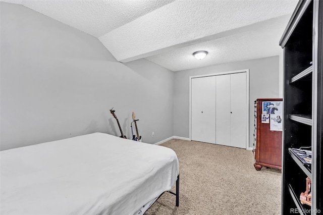 bedroom with a closet, lofted ceiling, carpet, and a textured ceiling