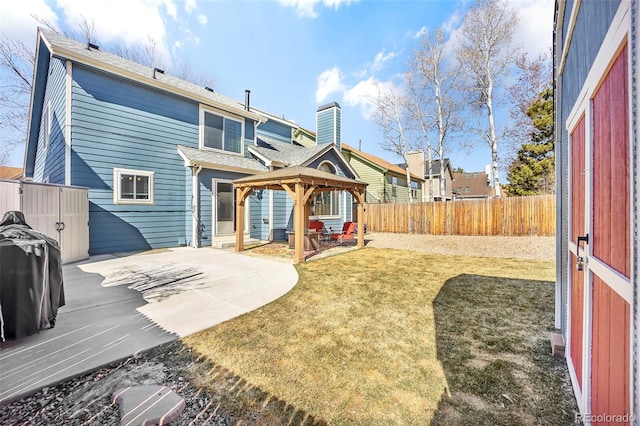 rear view of property featuring a lawn, a fenced backyard, a gazebo, a chimney, and a patio area