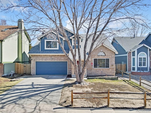 view of front of house with a fenced front yard, brick siding, an attached garage, and driveway