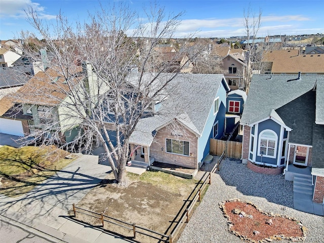 view of front of home featuring a residential view, a shingled roof, driveway, and fence