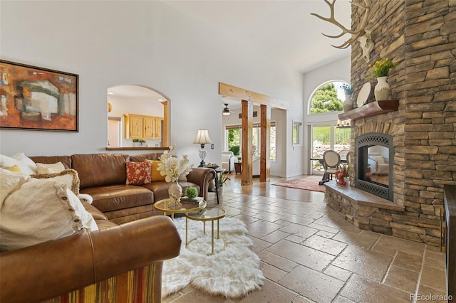2467 Spanish Oak Ter, Colorado Springs, CO 80920 - living room featuring high vaulted ceiling, stone tile floors, a fireplace, and arched walkways