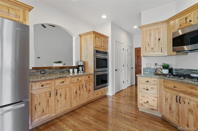 2467 Spanish Oak Ter, Colorado Springs, CO 80920 - kitchen featuring stainless steel appliances, light brown cabinets, light wood-type flooring, arched walkways, and recessed lighting