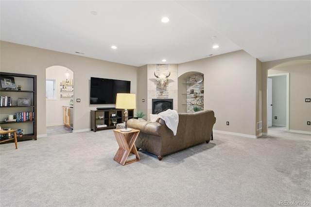 2467 Spanish Oak Ter, Colorado Springs, CO 80920 - living room featuring arched walkways, light carpet, recessed lighting, and a tile fireplace
