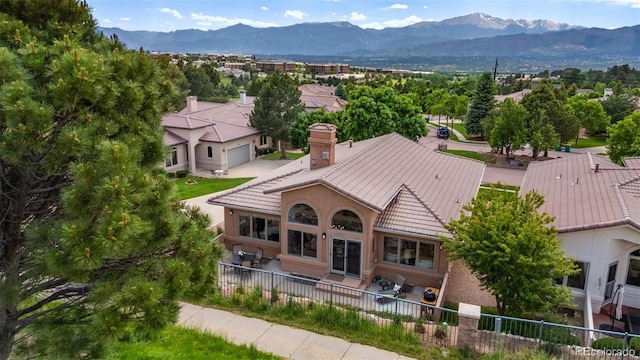 2467 Spanish Oak Ter, Colorado Springs, CO 80920 - rear view of house featuring a mountain view, a chimney, a tiled roof, and a garage