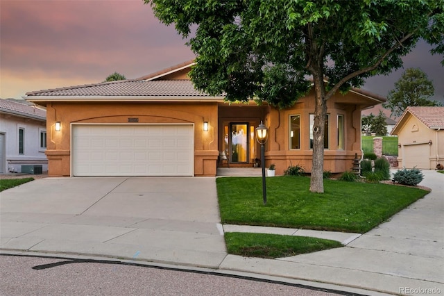 2467 Spanish Oak Ter, Colorado Springs, CO 80920 - view of front facade featuring driveway, an attached garage, stucco siding, a lawn, and a tile roof