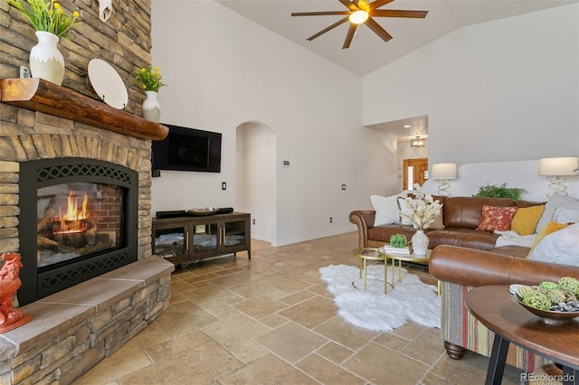 2467 Spanish Oak Ter, Colorado Springs, CO 80920 - living area with a ceiling fan, stone tile floors, high vaulted ceiling, arched walkways, and a stone fireplace
