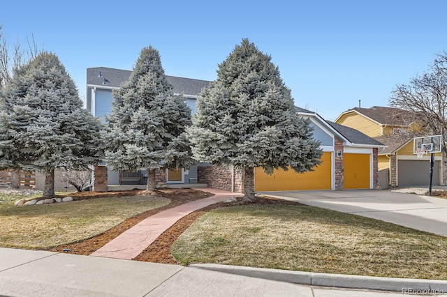 view of property hidden behind natural elements featuring concrete driveway, a front yard, a garage, and stone siding