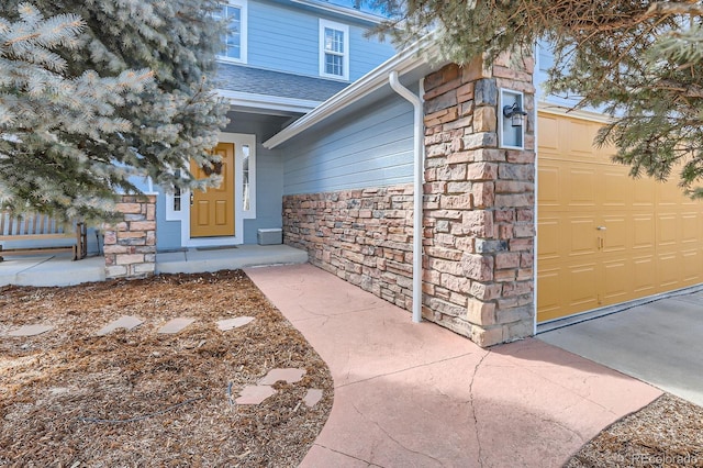 view of exterior entry with a garage and stone siding