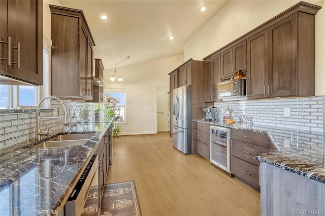 kitchen featuring light hardwood / wood-style floors, sink, dark stone counters, beverage cooler, and stainless steel fridge