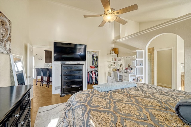 bedroom with light hardwood / wood-style flooring, vaulted ceiling, ceiling fan, a walk in closet, and a closet