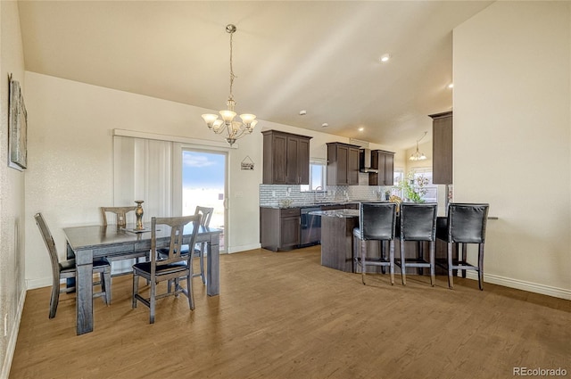 dining space with sink, vaulted ceiling, a chandelier, and light hardwood / wood-style floors