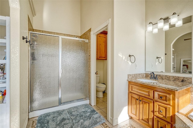 bathroom featuring vanity, toilet, a shower with door, and tile patterned flooring