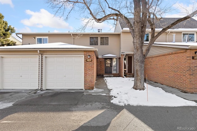 townhome / multi-family property featuring an attached garage, driveway, and brick siding